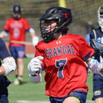 Crawdads youth lacrosse player in red jersey driving the ball past defenders from Pope Lacrosse during a game.