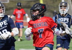 Crawdads youth lacrosse player in red jersey driving the ball past defenders from Pope Lacrosse during a game.